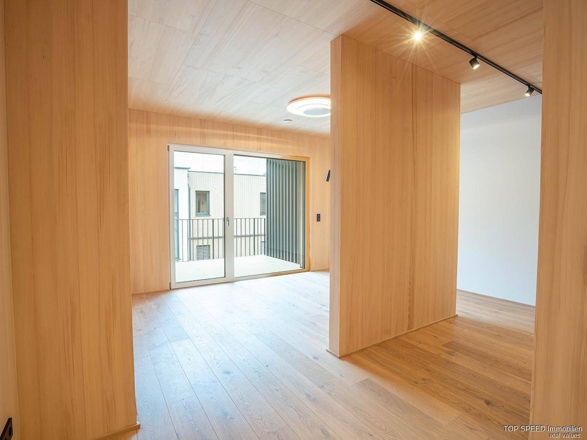 Heller Flurbereich mit Holzvertäfelung und Zugang zu einem kleinen Balkon, der viel Licht spendet.