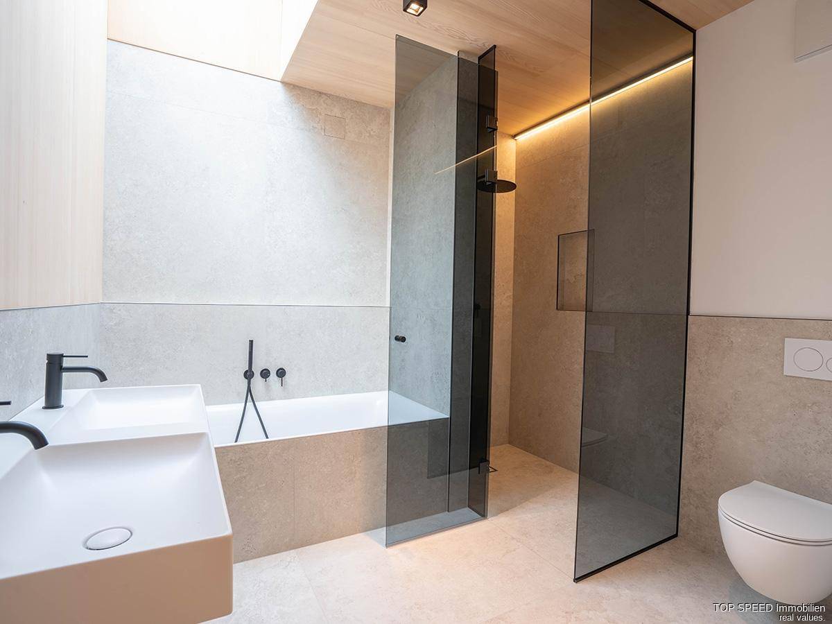 Modernes Badezimmer mit Badewanne, begehbarer Dusche, Wand-WC und eleganten Armaturen.