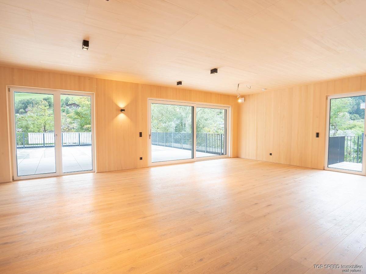 Großzügiger Wohnbereich mit Holzelementen und großen Schiebetüren, die zur Terrasse führen.