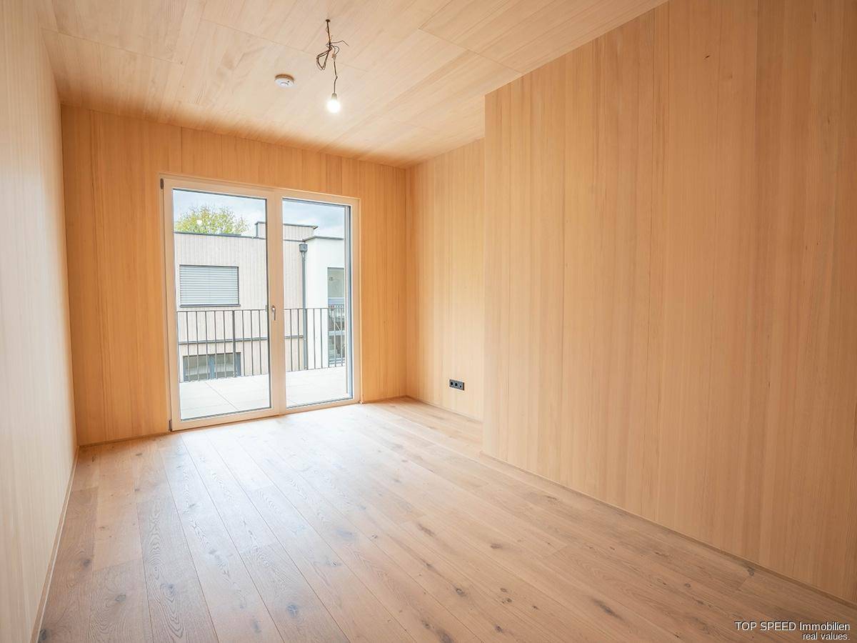 Helles Schlafzimmer mit Holzboden und Zugang zu einem Balkon, ideal für entspannte Morgenstunden.
