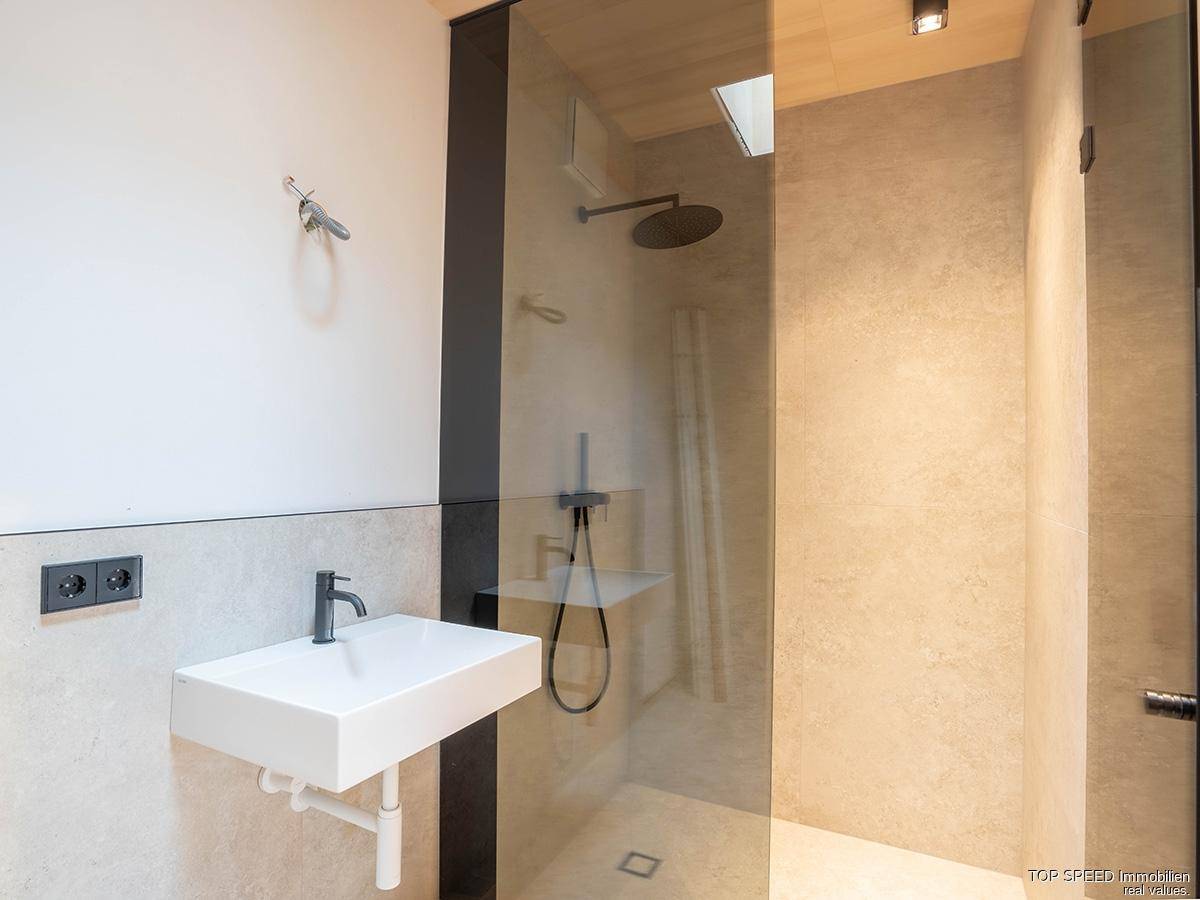 Elegantes Badezimmer mit begehbarer Dusche, modernem Waschbecken und hochwertigen Fliesen.
