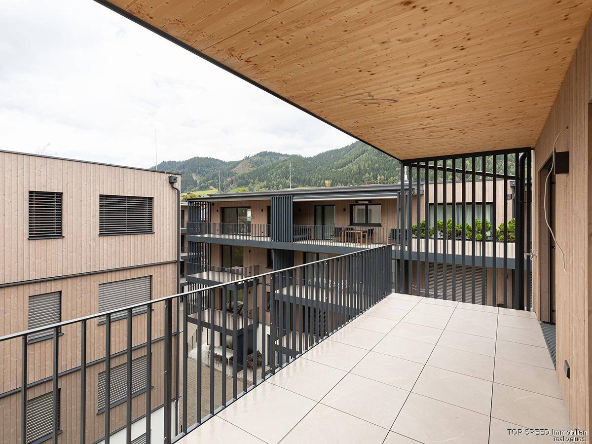 Geräumiger Balkon mit Fliesenboden und Blick auf die umliegenden Gebäude und Berge.