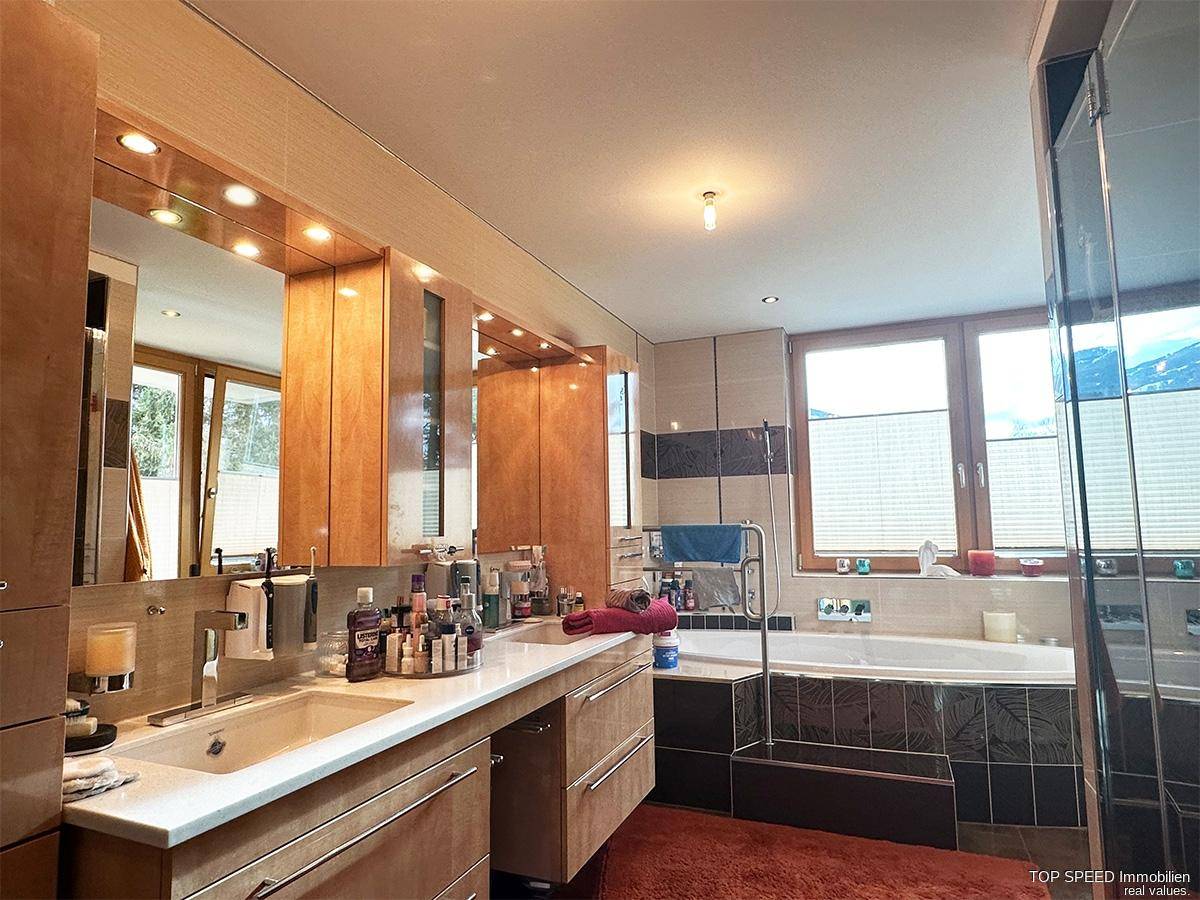 Geräumiges Badezimmer mit Doppelwaschbecken, Badewanne und Blick auf die verschneite Landschaft.