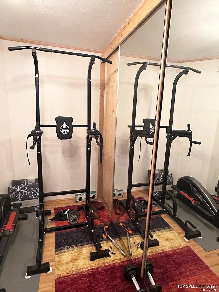 Kleiner Fitnessbereich mit Trainingsgeräten und Spiegelfronten für das Heimtraining.