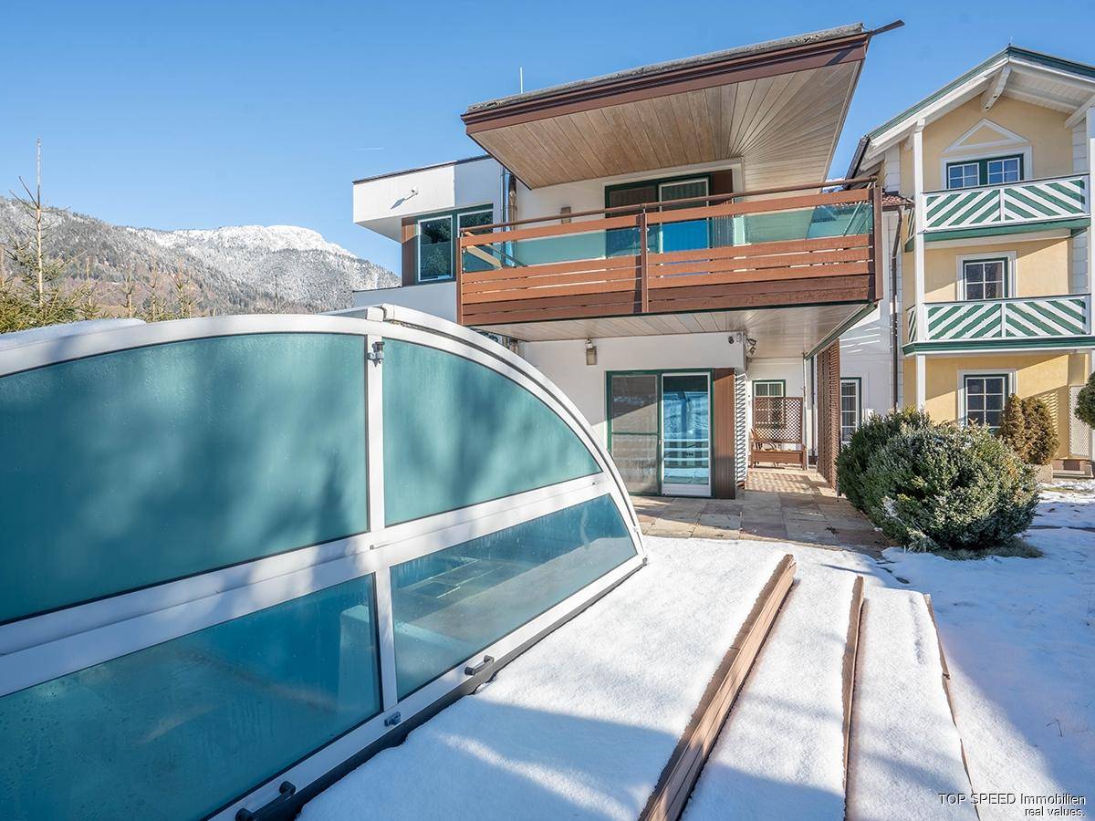 Ansicht des Hauses mit überdachtem Poolbereich und angrenzendem Nachbargebäude im Winter.