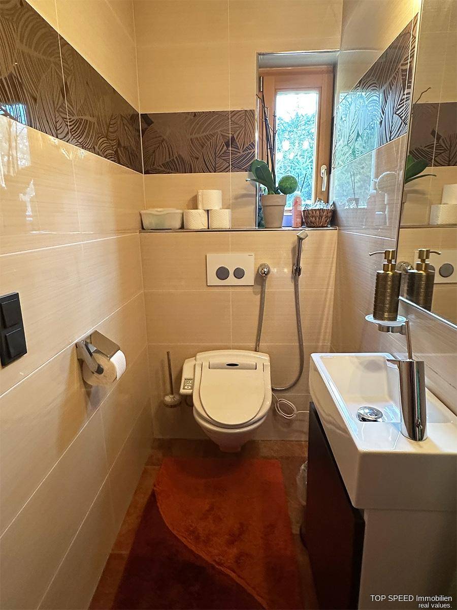 Helles Gäste-WC mit modernem Wand-WC, kleinem Waschbecken und Fenster.