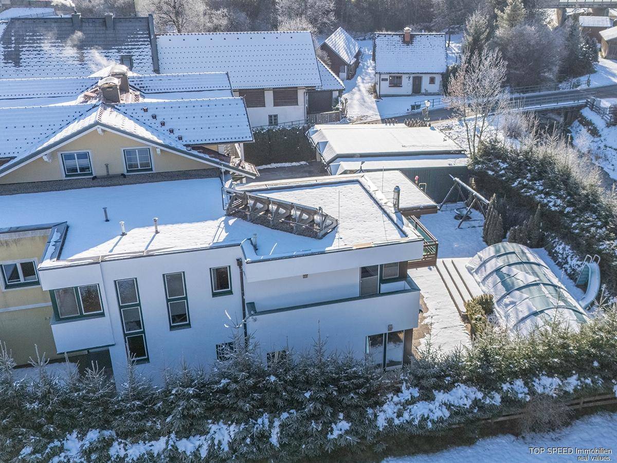 Weitläufige Luftaufnahme des Anwesens mit Pool und umliegenden Häusern in verschneiter Umgebung.