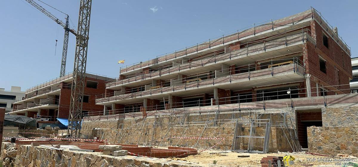 Mehrstöckiges Gebäude im Rohbau mit sichtbaren Ziegeln und Beton, daneben ein großer Baukran.