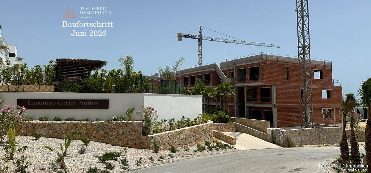 Eingangsbereich der Limonero Green Suites mit Landschaftsgestaltung und einem Gebäude im Bau.