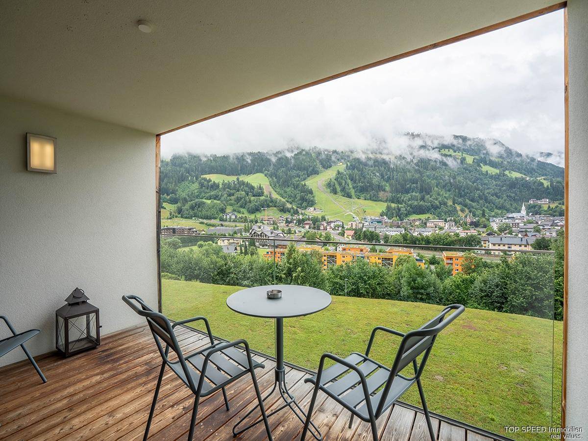 Balkon mit Holzboden, Sitzgelegenheiten und Panoramablick auf die Berge und das Tal.