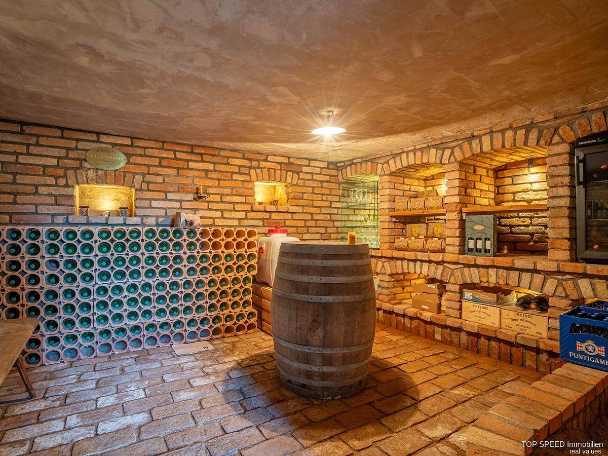Gemütlicher Weinkeller mit Ziegelwänden, Fliesenboden und Holzfass, ideal zur Weinlagerung.