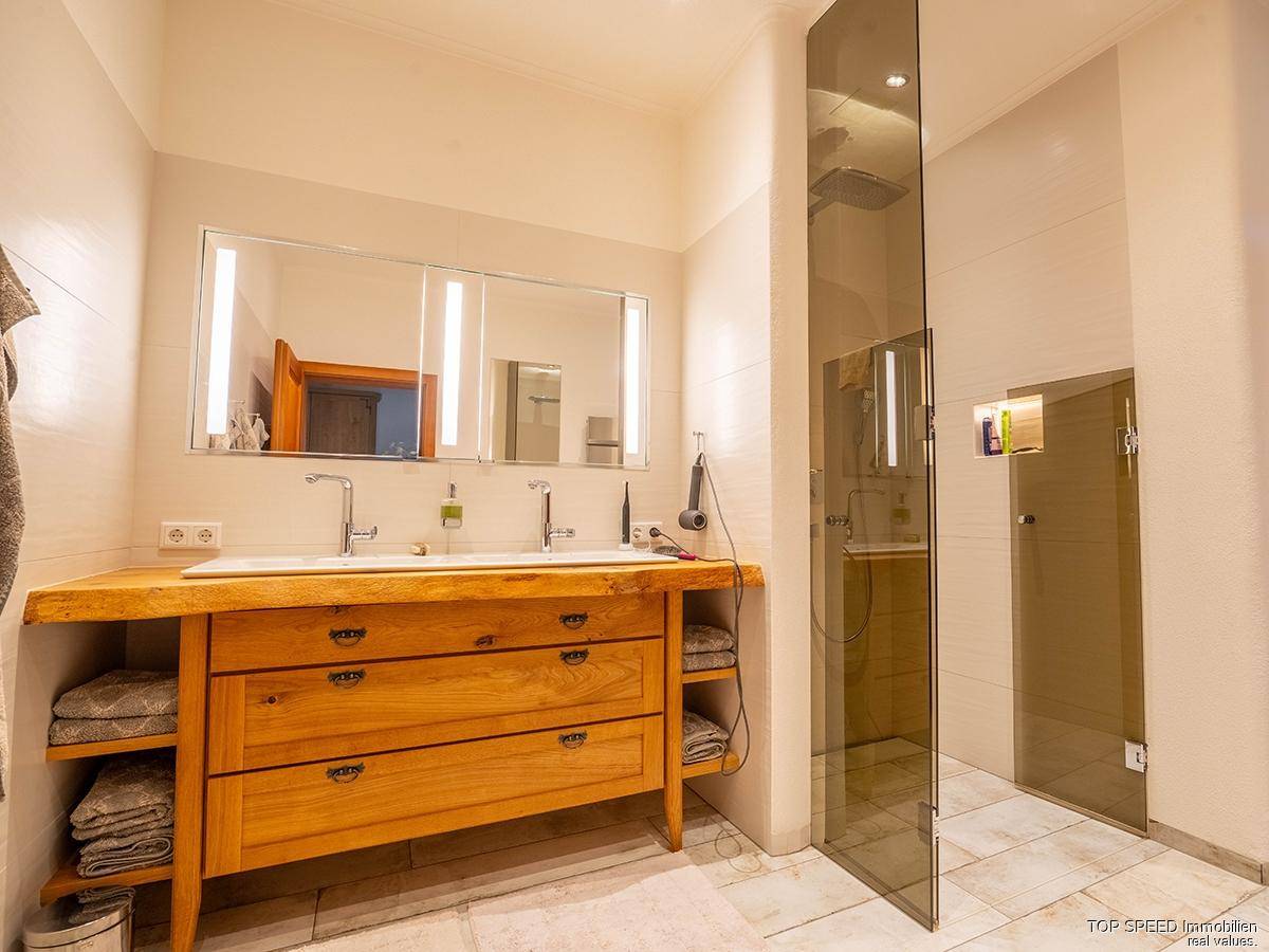 Modernes Badezimmer mit Holzwaschtisch, Doppelwaschbecken und begehbarer Dusche, hell und geräumig.