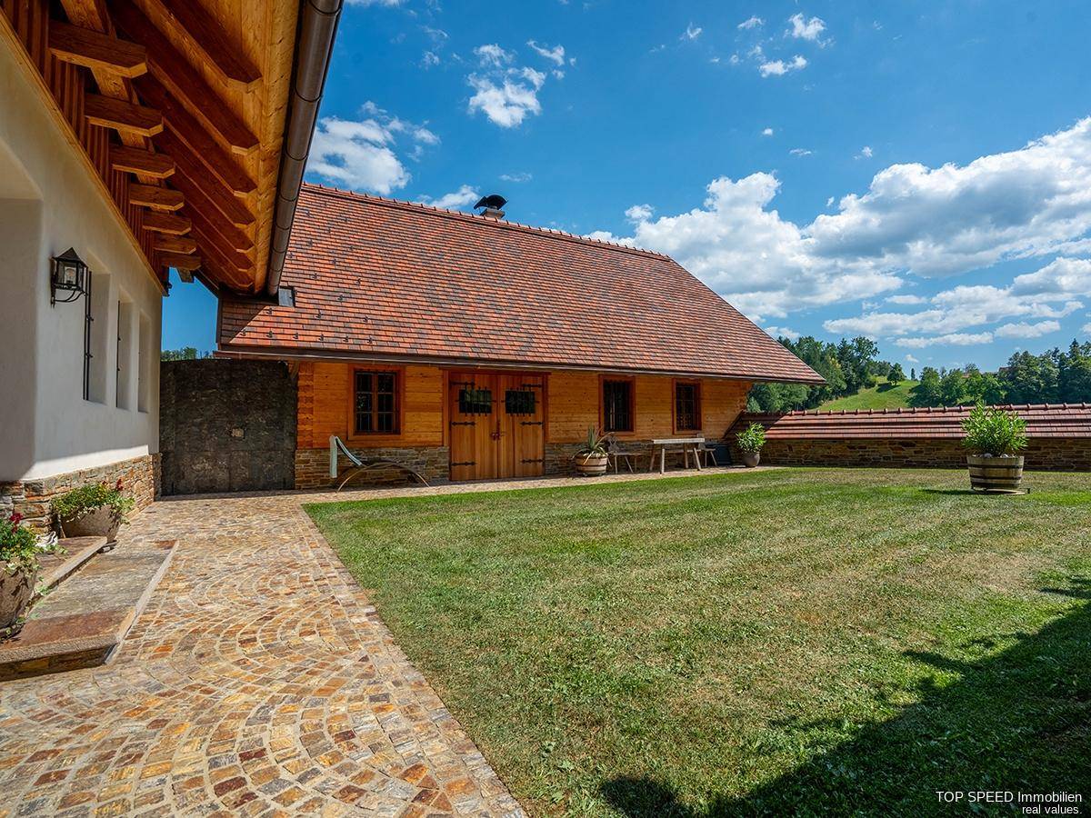 Weitläufiger Rasenbereich mit dekorativem Steinweg vor einem charmanten Holzhaus unter blauem Himmel.