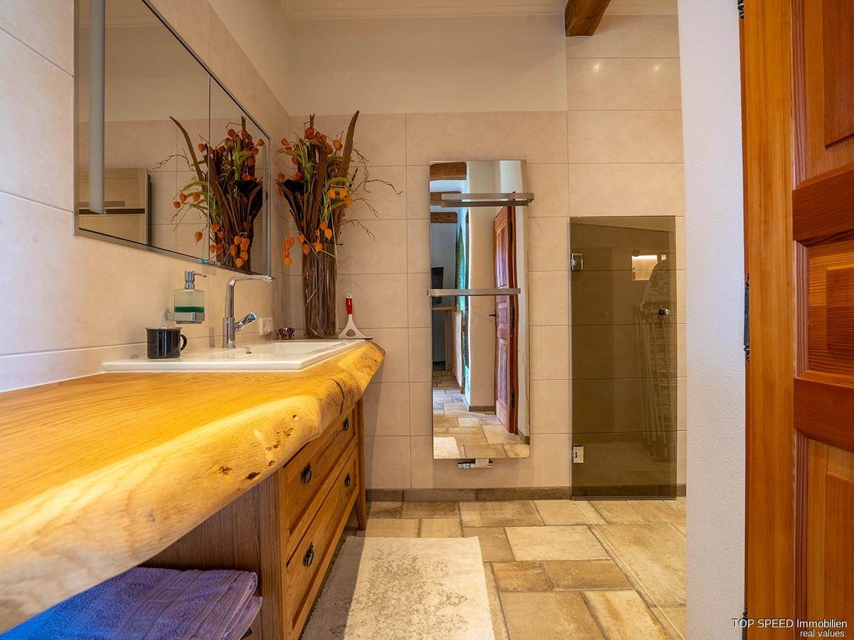 Modernes Badezimmer mit Holzwaschtisch, Einzelwaschbecken und begehbarer Dusche, hell und funktional.
