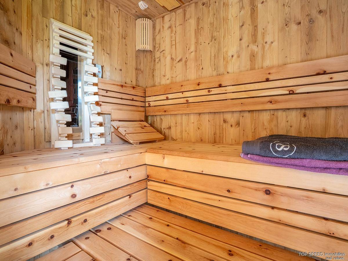 Geräumige Holzsauna mit mehreren Bänken und indirekter Beleuchtung, ideal zur Entspannung.