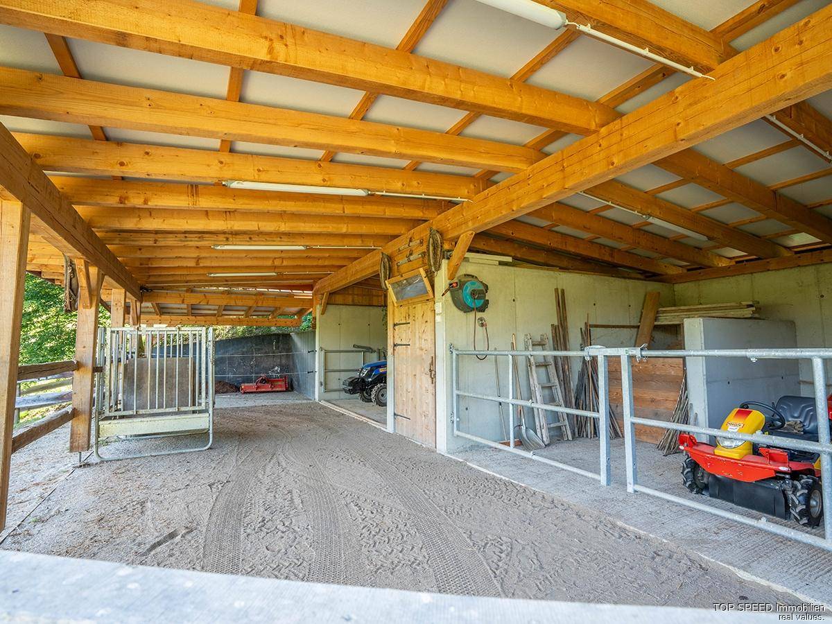 Geräumiger Holzstall mit mehreren Boxen und Lagerflächen, ideal für landwirtschaftliche Nutzung.