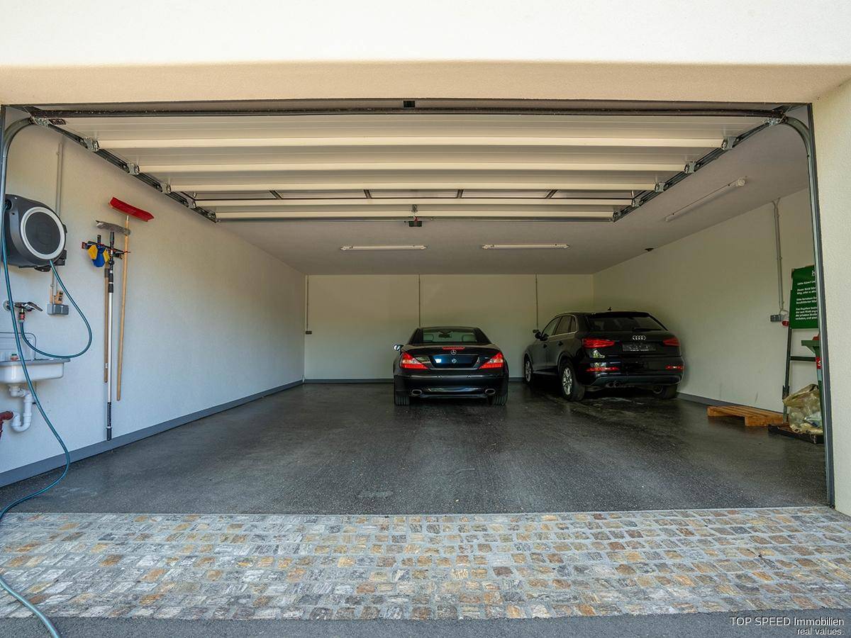 Geräumige Doppelgarage mit zwei Fahrzeugen, Waschbecken und Stauraum für Werkzeuge.