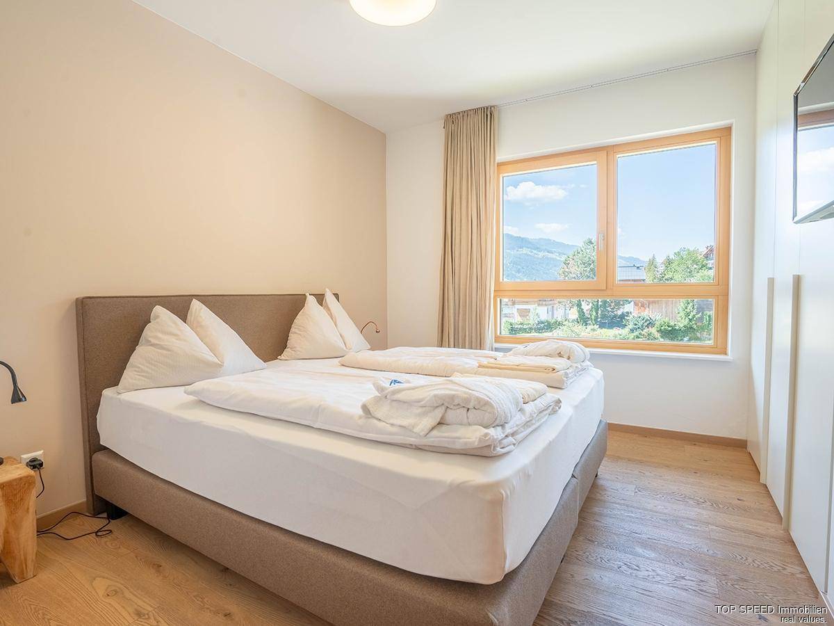 Helles Schlafzimmer mit Doppelbett, Holzboden und einem Fenster, das einen schönen Bergblick bietet.