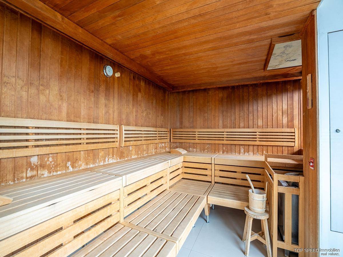 Traditionelle Holzsauna mit mehreren Bänken und einem Saunaofen für entspannende Momente.