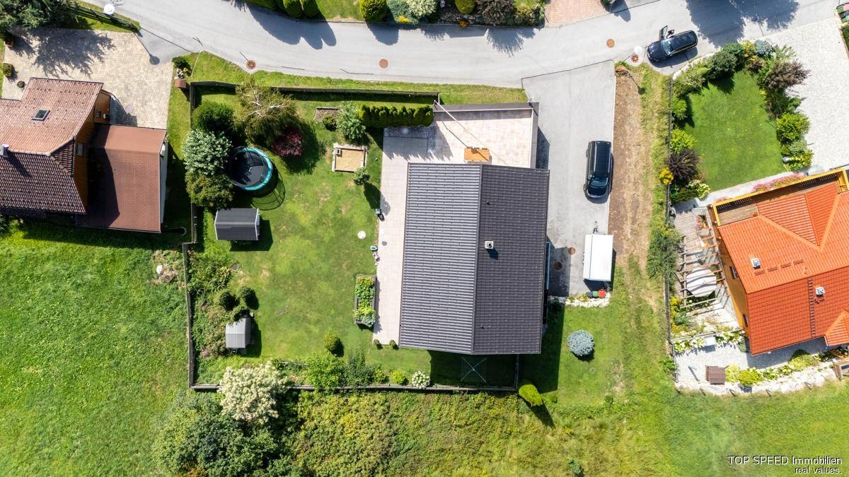 Luftaufnahme des Anwesens mit Haus, Garten, Zufahrt und umliegender grüner Landschaft.