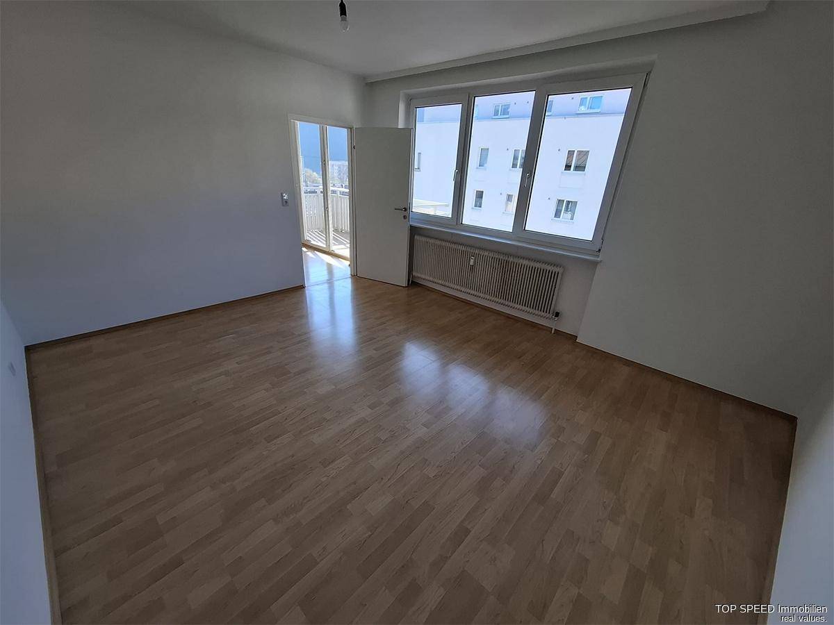 Helles Schlafzimmer mit Parkettboden und großen Fenstern, bereit zur individuellen Gestaltung.