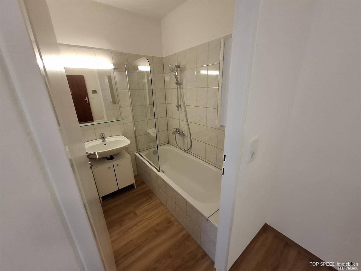 Funktionales Badezimmer mit Badewanne, Duschvorrichtung und Waschbecken.