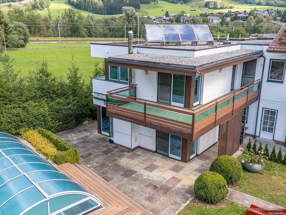 Luftaufnahme des Hauses mit Flachdach, Balkonen und Solaranlage auf dem Dach.