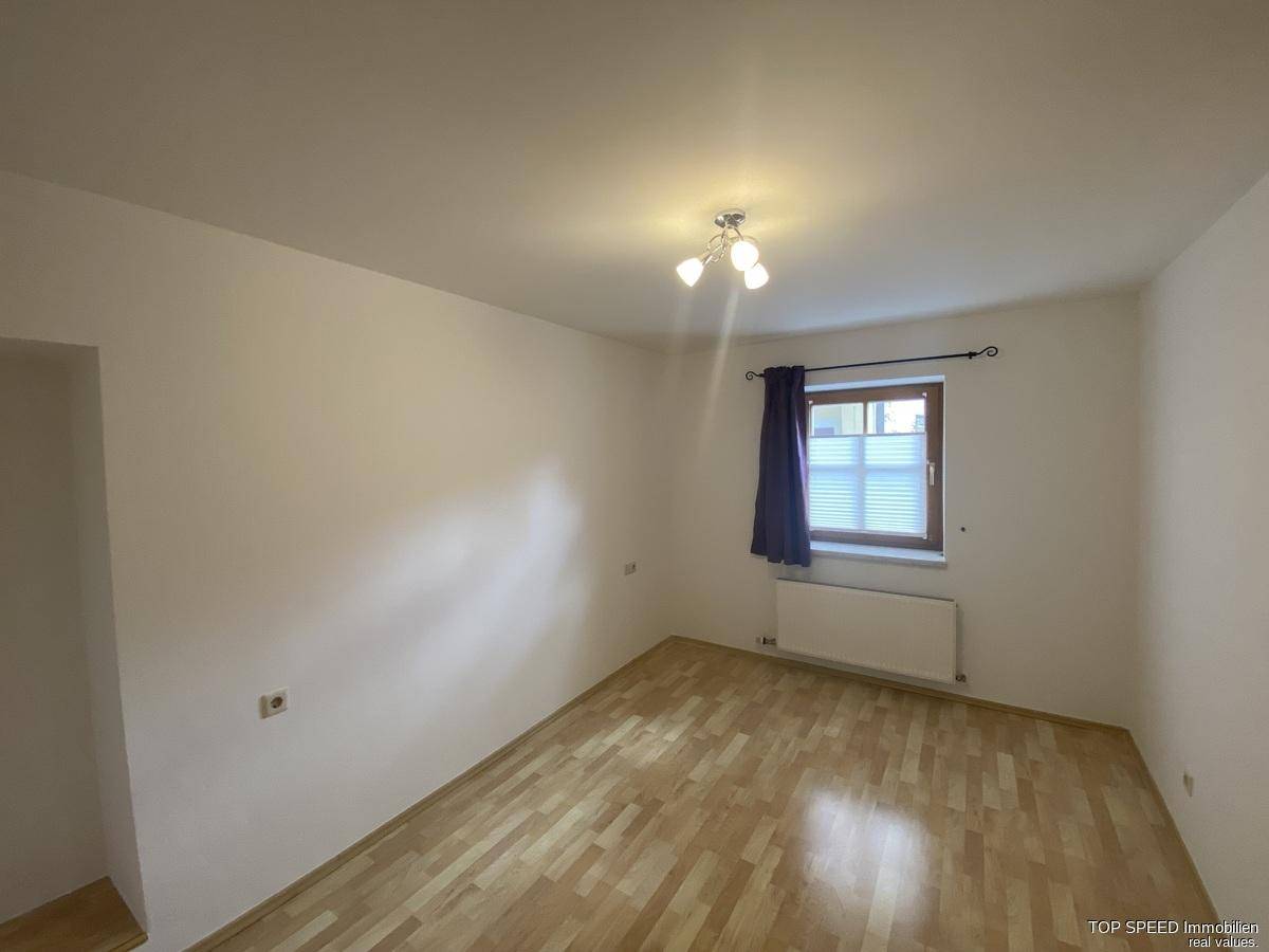 Helles Schlafzimmer mit Laminatboden und einem Fenster, das für natürliches Licht sorgt.