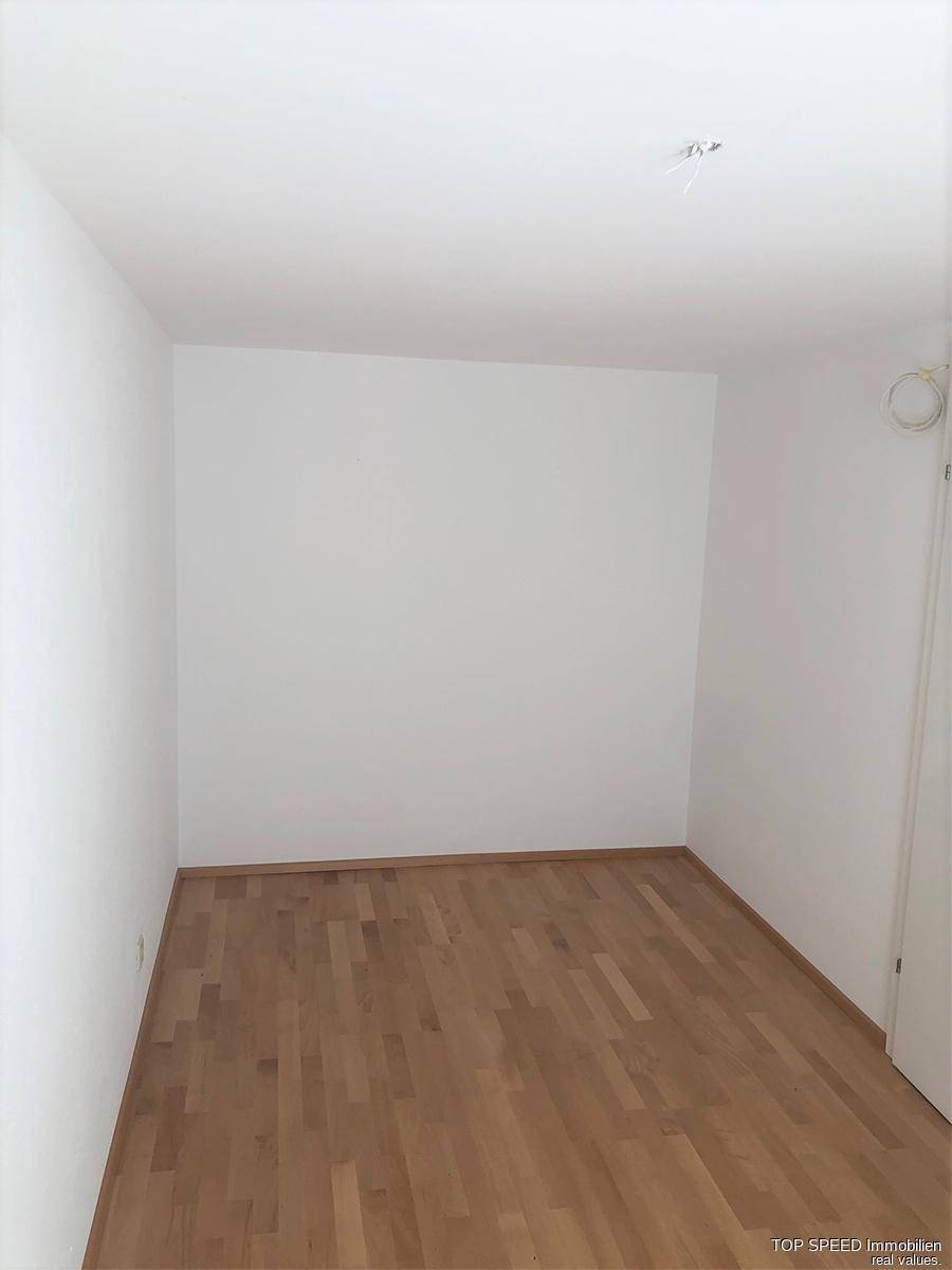 Leerer Raum mit Laminatboden und weißen Wänden, bereit zur individuellen Gestaltung.