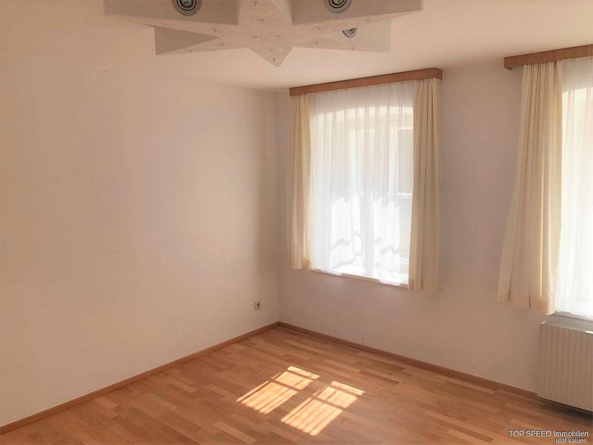 Gemütliches Schlafzimmer mit Laminatboden, hellen Wänden und dekorativer Deckenleuchte.