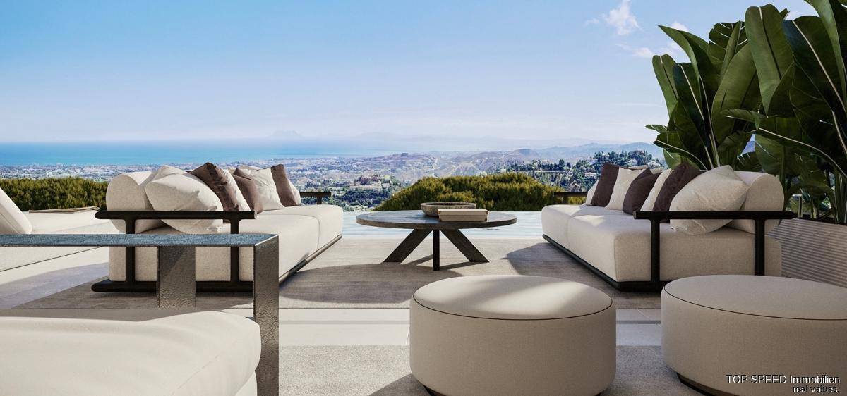 Große möblierte Terrasse mit Meerblick und bequemen Lounge-Möbeln.