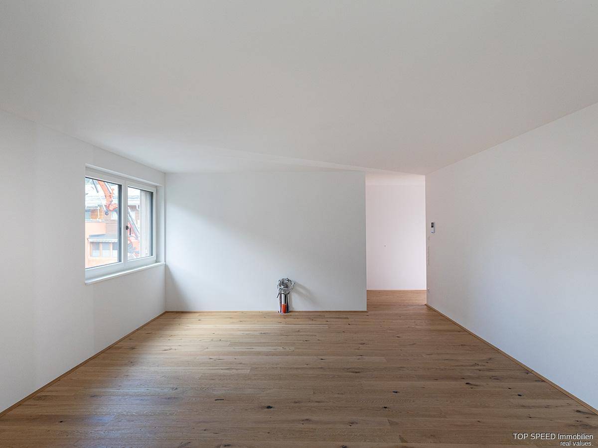 Langer, heller Wohnbereich mit Holzboden und viel Tageslicht von der Seite.