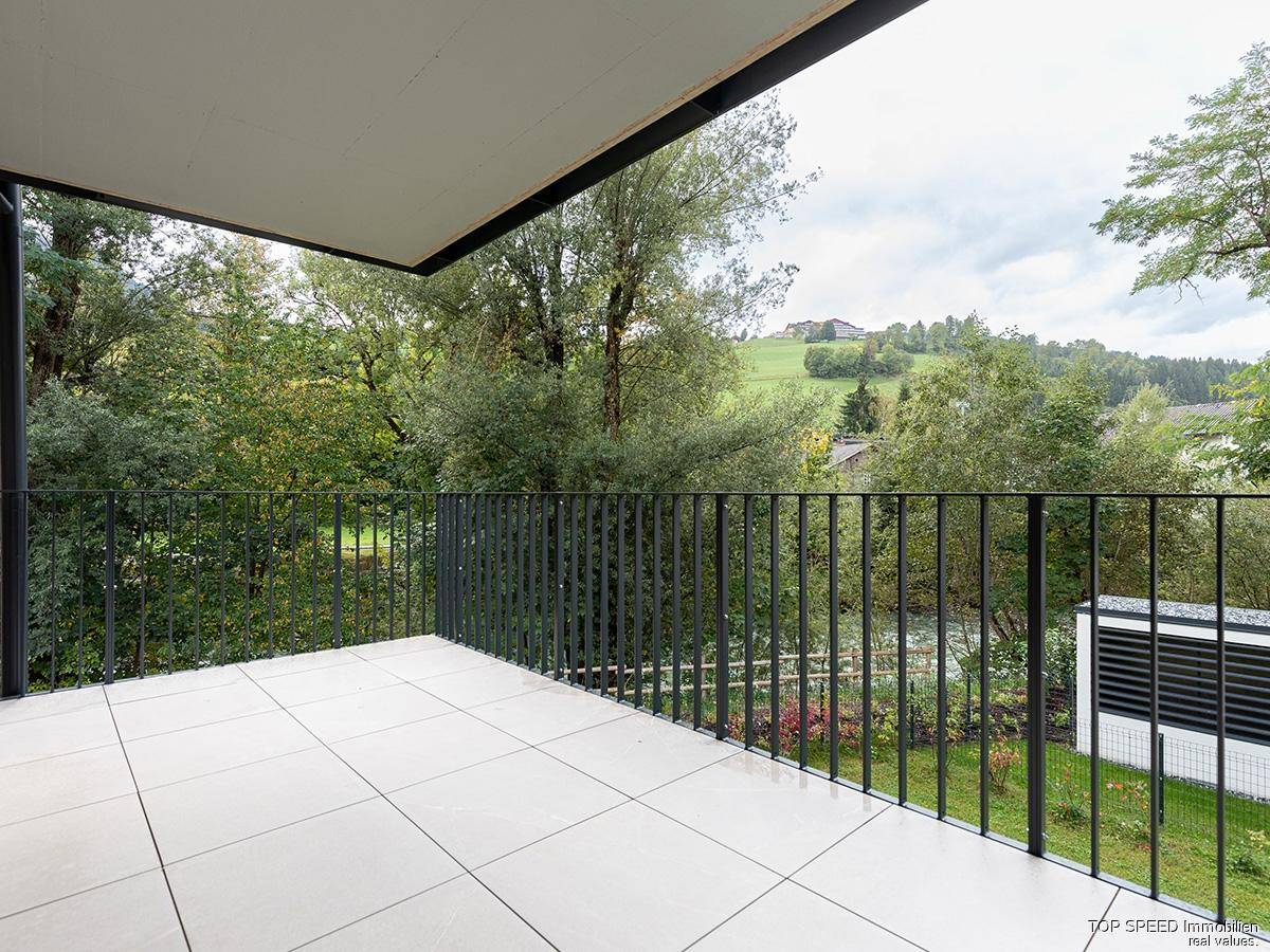 Geräumiger Balkon mit Fliesenboden und weitem Blick auf die grüne Landschaft und Hügel.