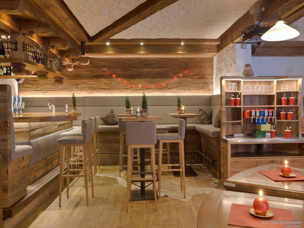 Rustikale Bar mit Holztresen, hohen Barhockern und traditioneller Holzverkleidung.
