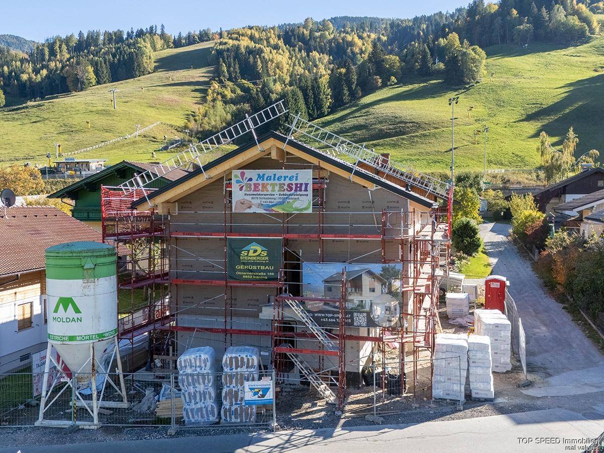 Detailansicht des im Bau befindlichen Gebäudes mit Gerüst und Werbebannern.