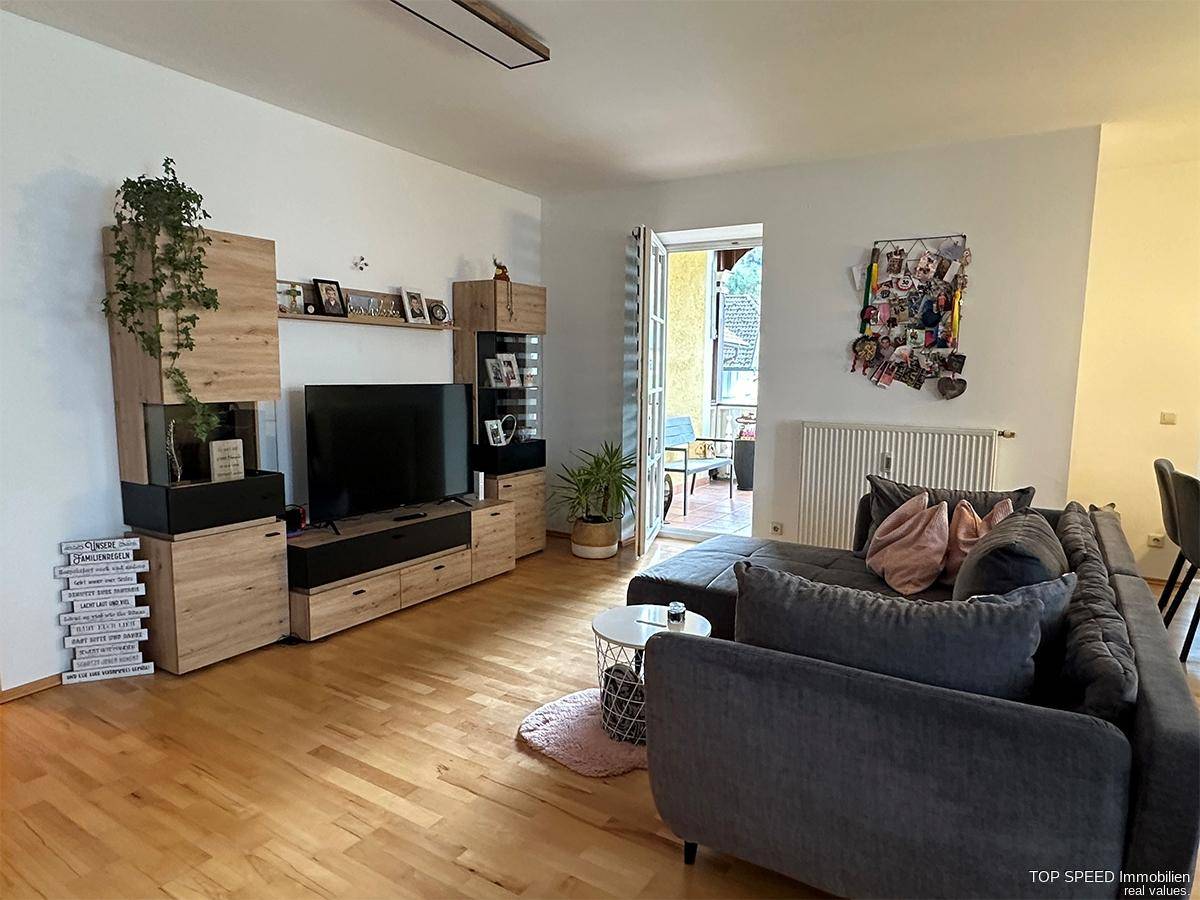 Gemütliches Wohnzimmer mit großem Sofa, modernem TV-Möbel und Zugang zu einem Außenbereich.