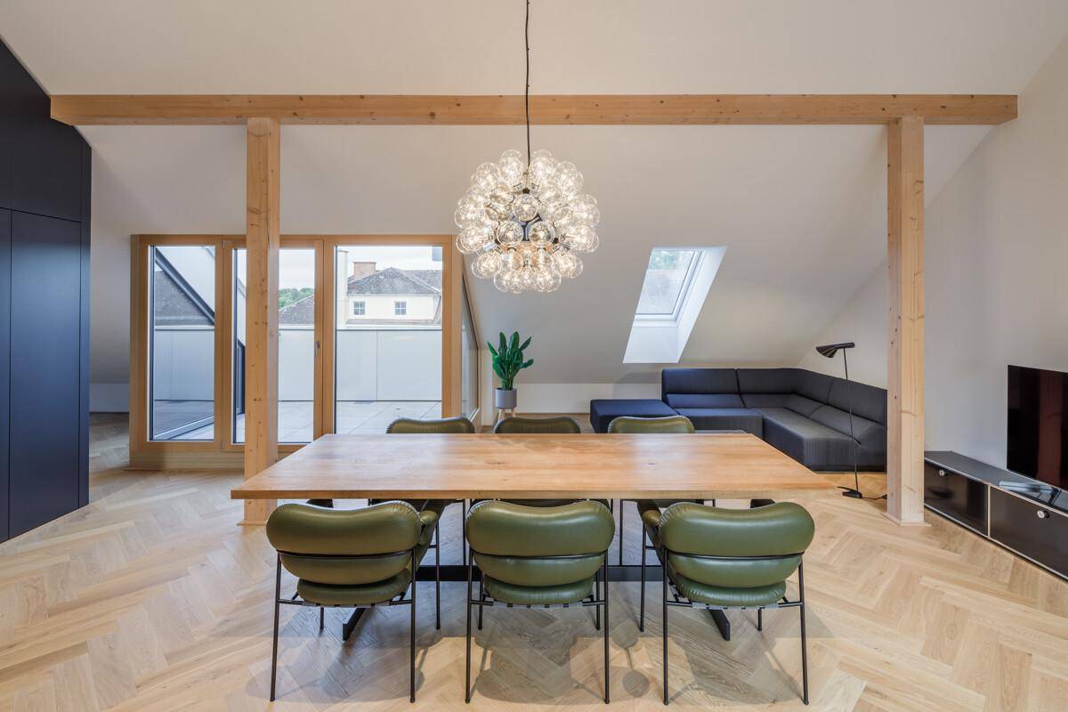 Geräumiger Wohn-Essbereich mit Holzbalken, Parkettboden und Zugang zur Terrasse.