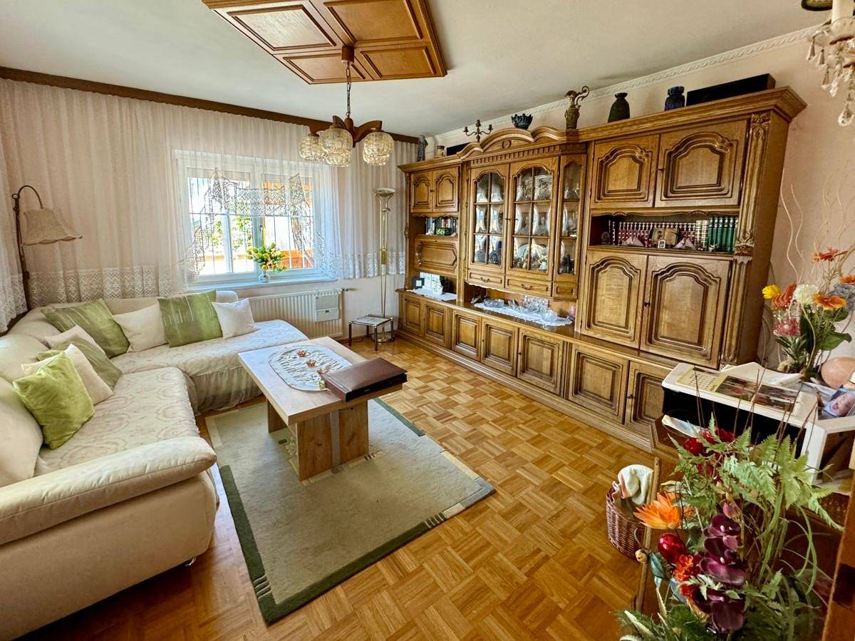 Klassisches Wohnzimmer mit Parkettboden, großem Holzschrank und bequemer Sofagarnitur.