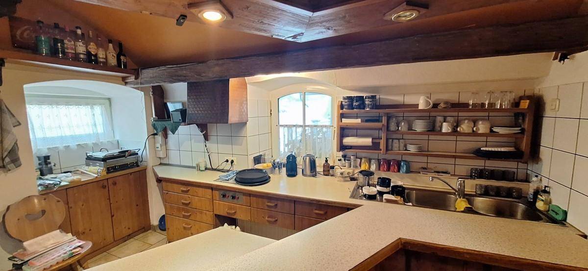 Gut ausgestattete Küche mit Holzschränken, Fliesenboden und Blick auf den Außenbereich.