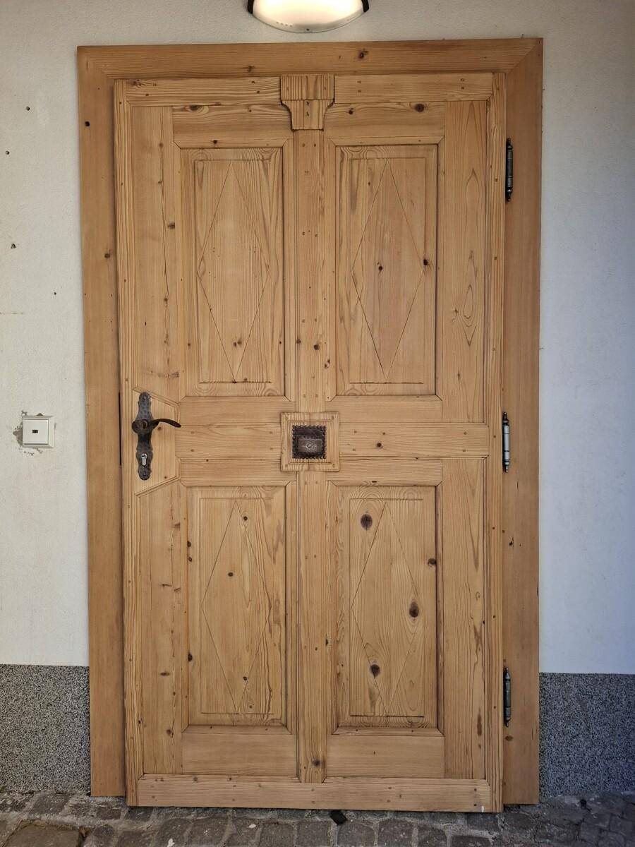 Rustikale Holzeingangstür mit traditionellen Schnitzereien und Metallbeschlägen.