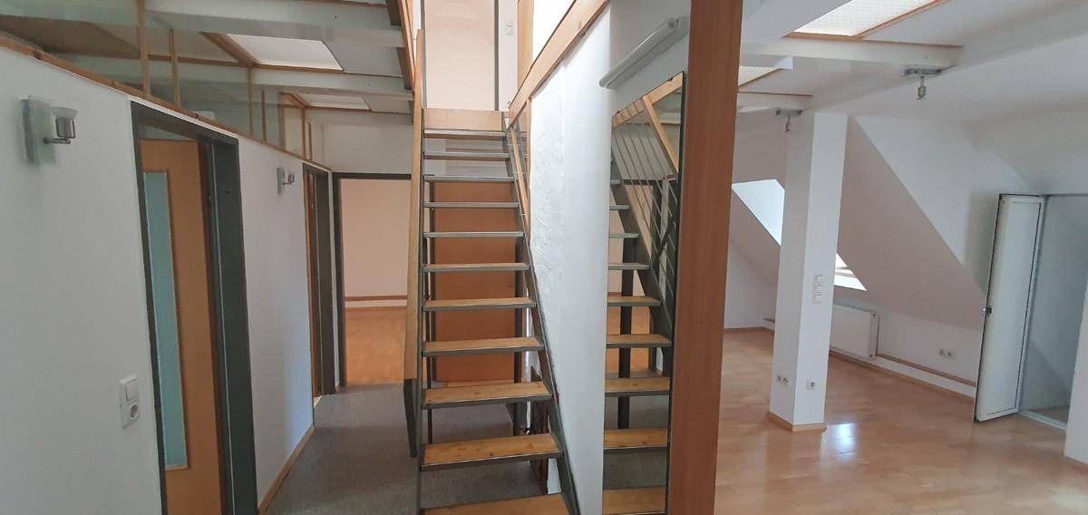 Offener Innenbereich mit Holztreppe und Dachfenstern, der verschiedene Ebenen verbindet.