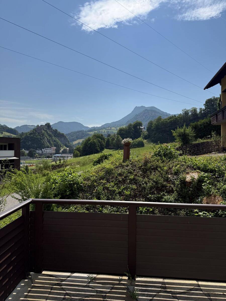 Weitläufiger Ausblick auf die grüne Berglandschaft unter blauem Himmel.