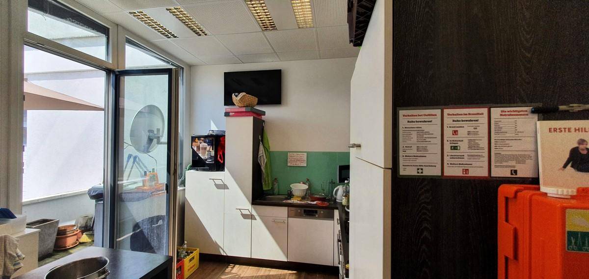 Kleine Küchenzeile mit Spülmaschine und direktem Zugang zu einem Außenbereich mit Sonnenschirm.