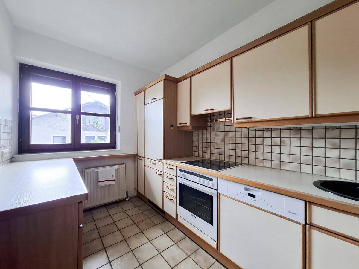 Helle Küche mit Fenster, Einbauschränken und integrierten Küchengeräten.