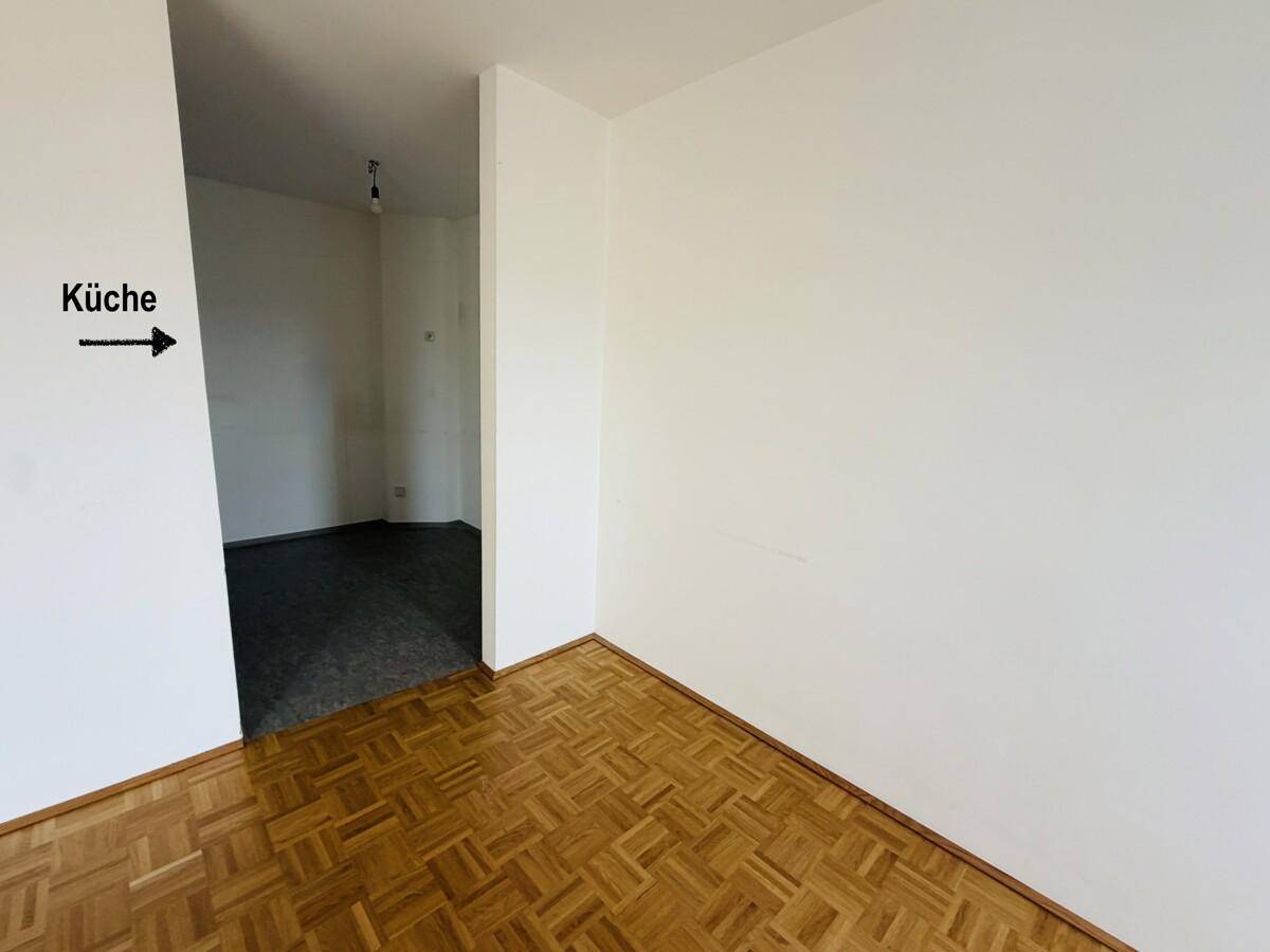Heller Wohnbereich mit Parkettboden und direktem Zugang zu einem gefliesten Raum.