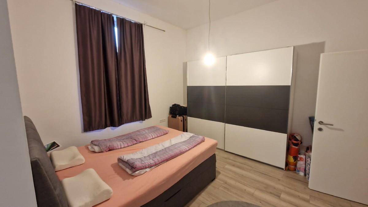 Schlafzimmer mit Doppelbett, großem Kleiderschrank und Laminatboden, gut beleuchtet.