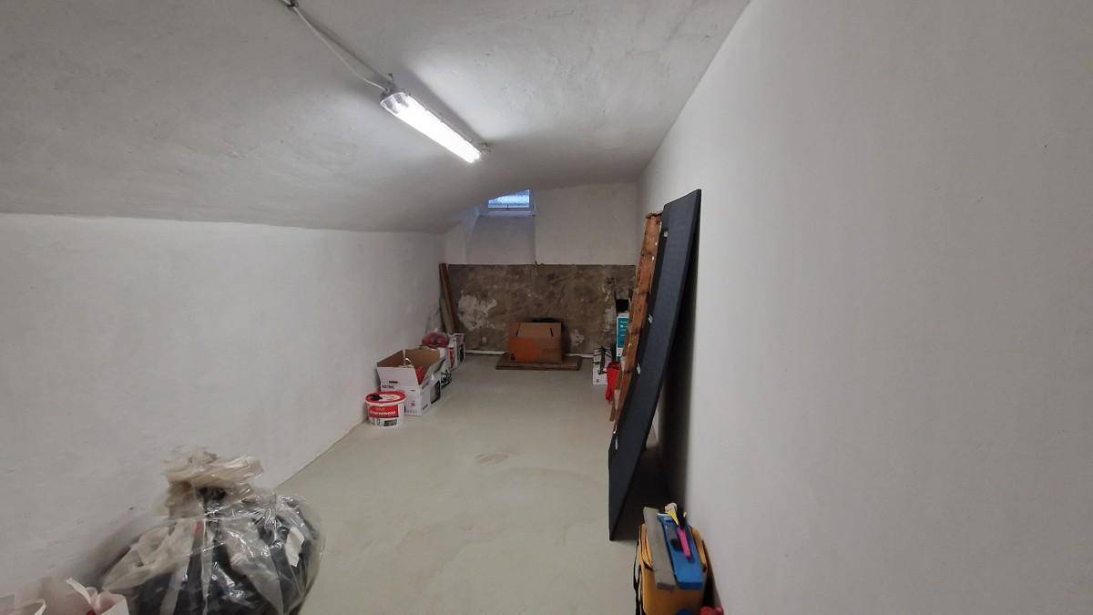 Geräumiger Kellerraum mit weiß gestrichenen Wänden und kleinem Fenster, ideal als Lager.
