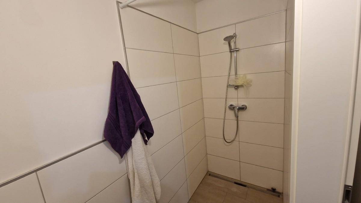 Funktionale Duschkabine mit weißen Fliesen und einfacher Armatur in einem Badezimmer.