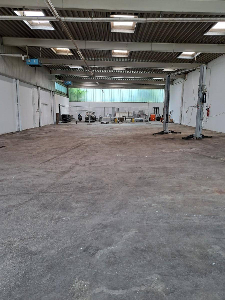 Geräumige Werkstatthalle mit hohen Decken, Oberlichtern und zwei Hebebühnen für Fahrzeuge.