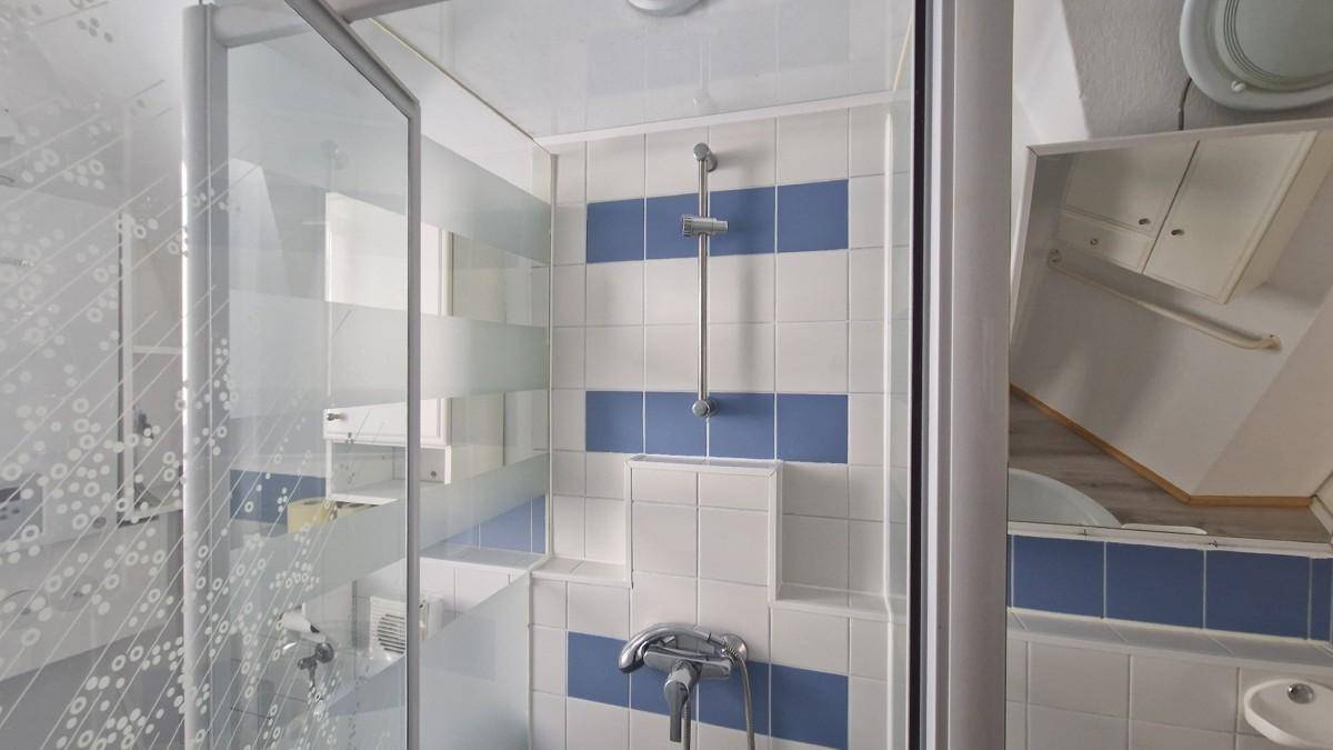 Duschkabine mit weiß-blauen Fliesen und moderner Armatur in einem Badezimmer.